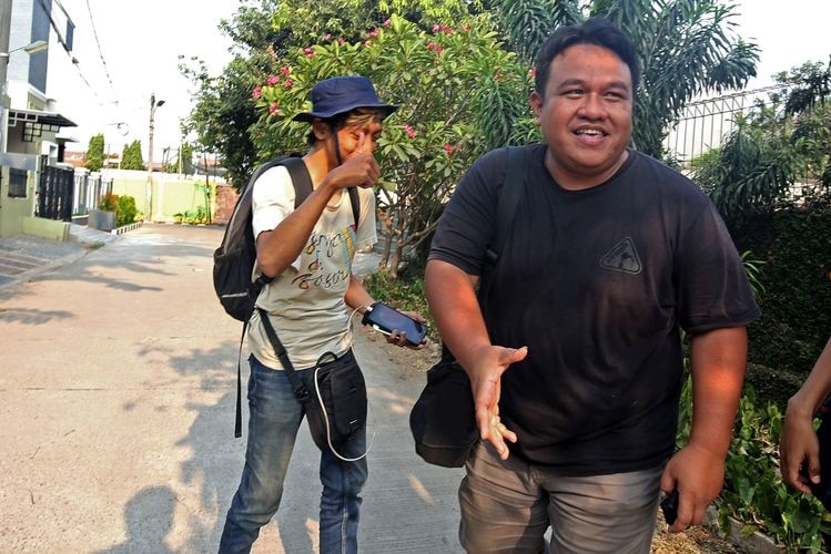 Indonesian filmmaker Dandhy Laksono smiles and gestures as journalists take photos of him.