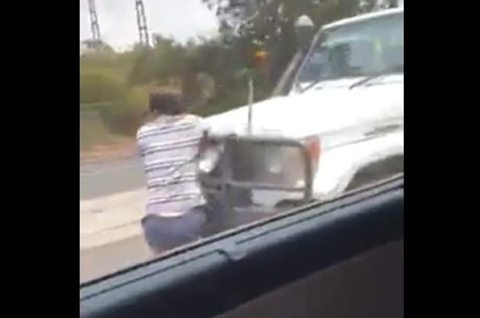 Man clings to front of car