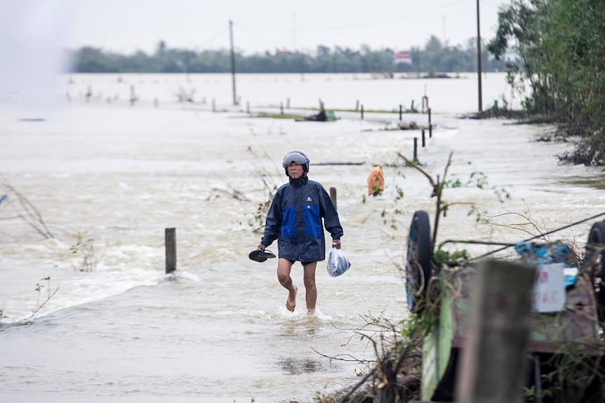 A local resident walks through the floodwater wearing a rain cover.