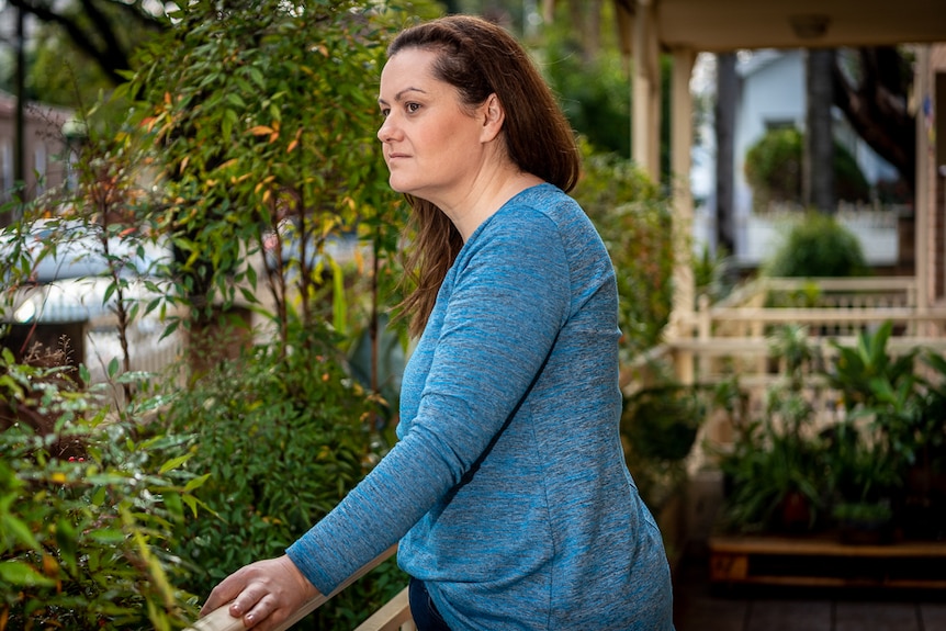 A woman on a balcony looking out into the distance.