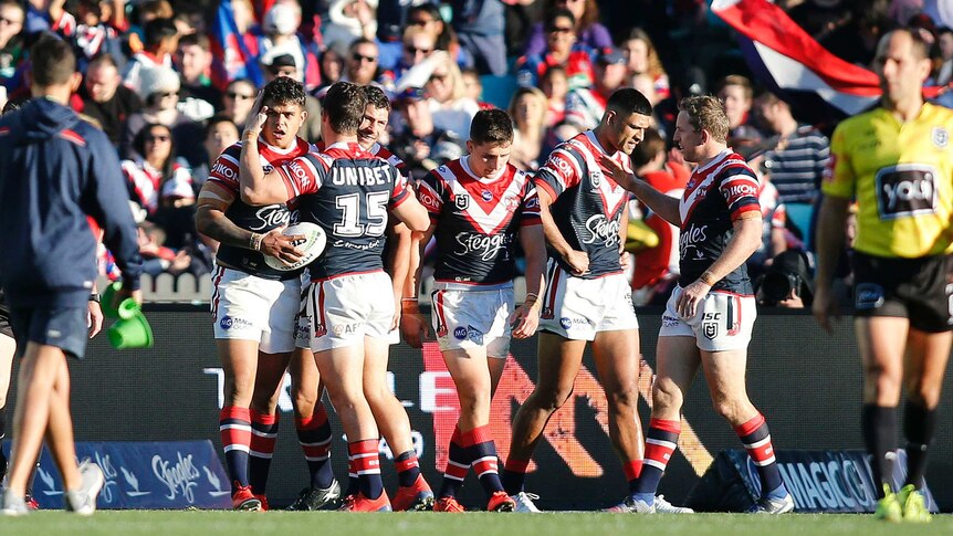 A player gets patted on the head by his teammates after scoring a try.