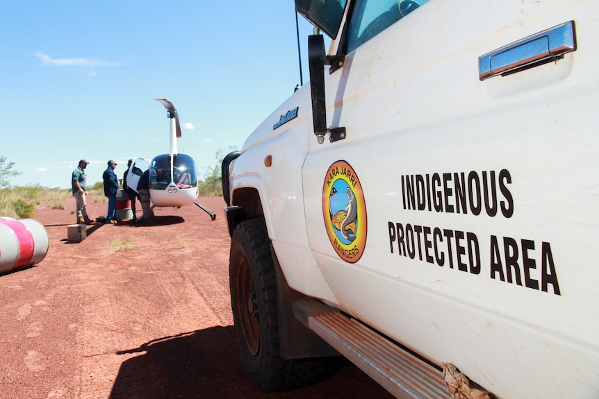 A vehicle with an Indigenous Protected Area sign parked near a helicopter.