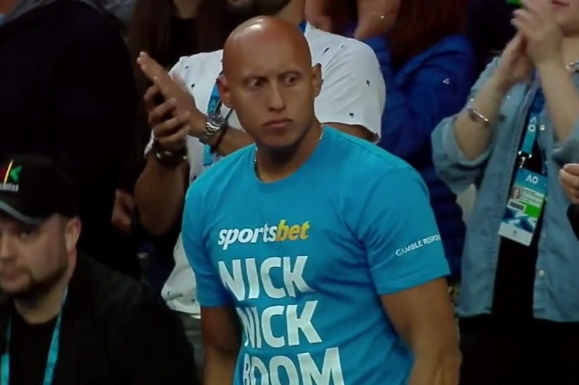 Christos Kyrgios wears a blue shirt with the words 'Sportsbet Nick Nick Boom' on it.