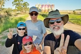 Sam and Keiran Lusk with their sons Ellery and Aubrey, stand in front of art painted on silos in outback Queensland.