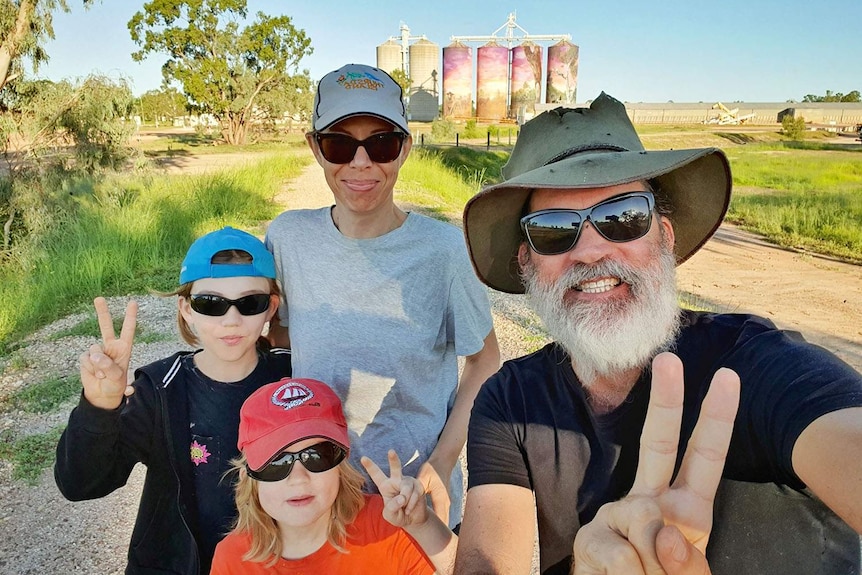 Sam and Keiran Lusk with their sons Ellery and Aubrey, stand in front of art painted on silos in outback Queensland.