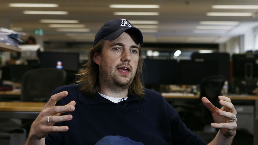 A young entrepreneur wearing a cap gestures as he speaks.