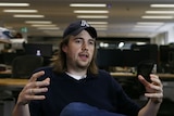 A young entrepreneur wearing a cap gestures as he speaks.