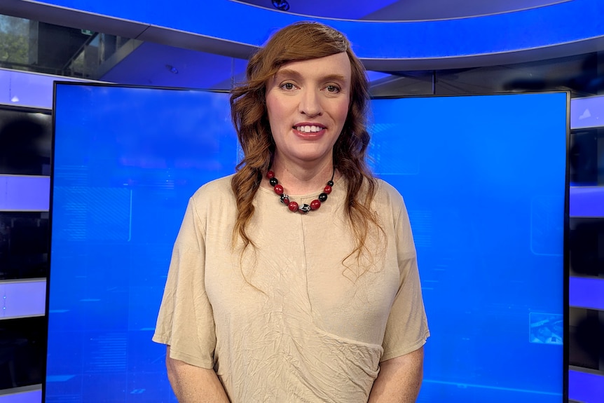 Una foto de Kate Doak en un estudio de televisión parada frente a una pantalla azul.