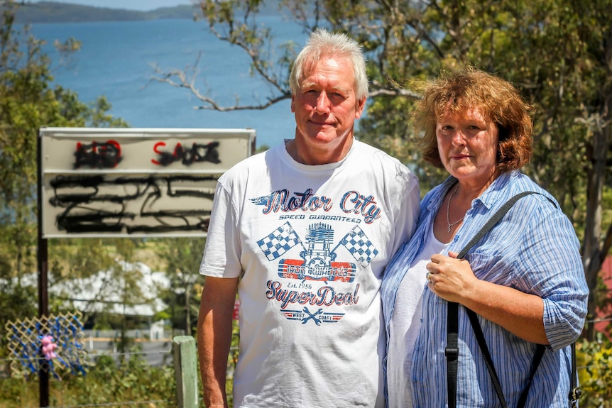 A man and woman stand in front of a view of the ocean