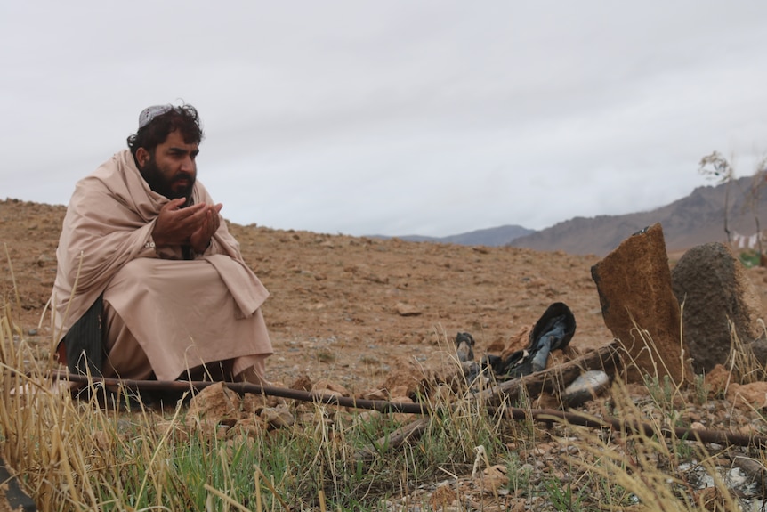 a man praying by a crude grave