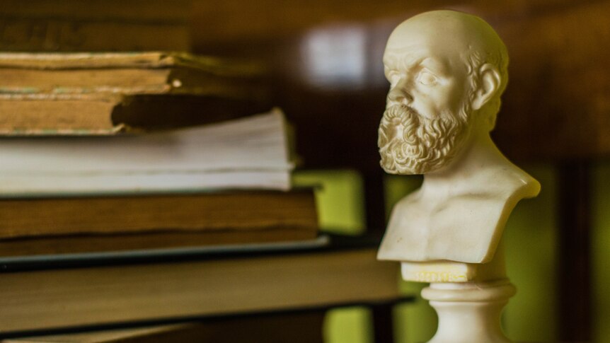 An alabaster bust of Socrates sits next to a pile of books.