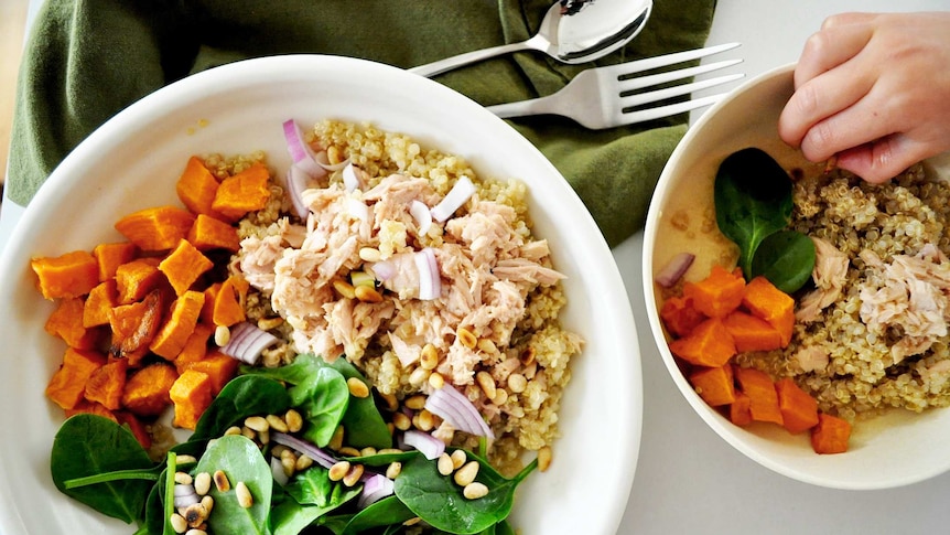 Two quinoa salad bowls with sweet potato, baby spinach, tinned tuna, pine nuts and red onion to illustrate our simple recipe.
