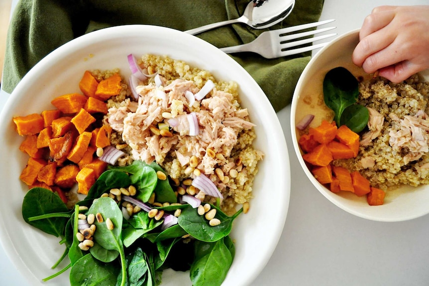 Two quinoa salad bowls with sweet potato, baby spinach, tinned tuna, pine nuts and red onion to illustrate our simple recipe.