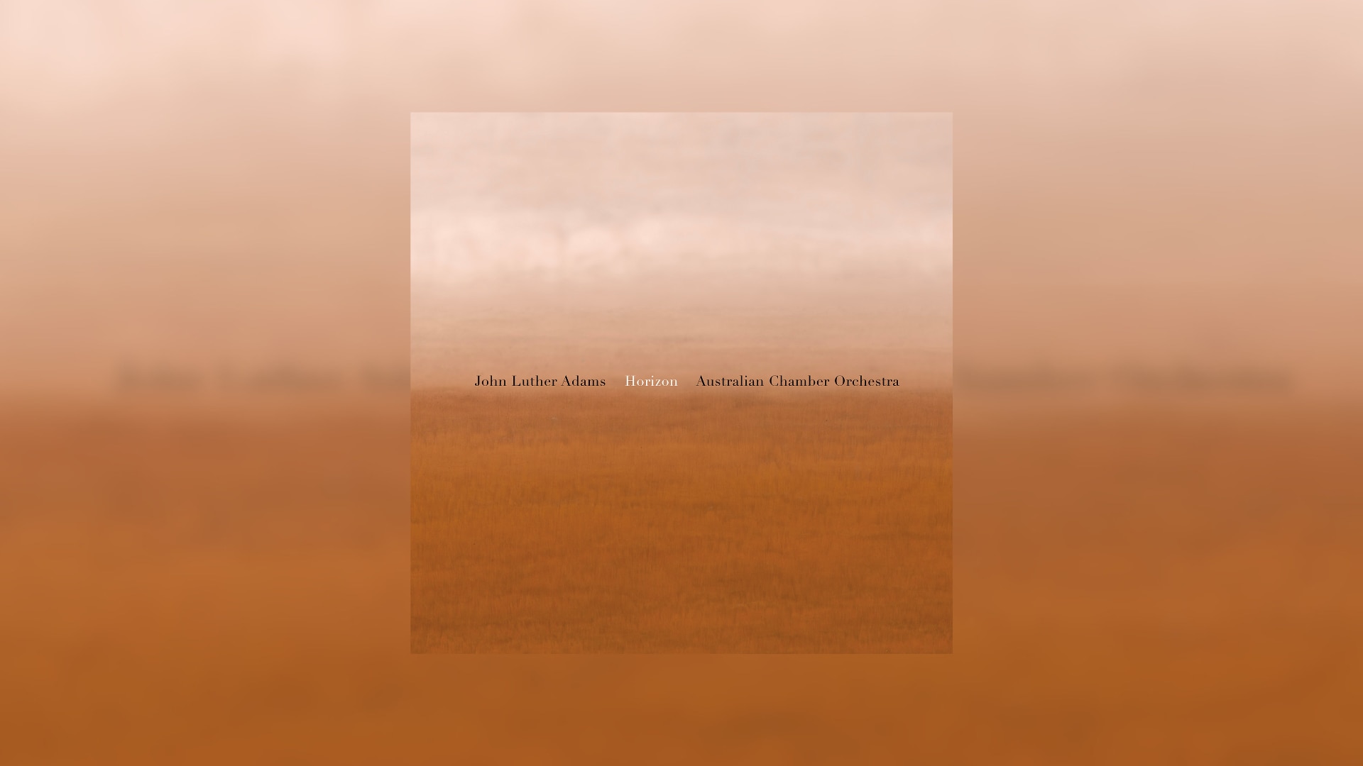 Blurred, abstract image of pale salmon coloured sky over burnt orange desert sand.