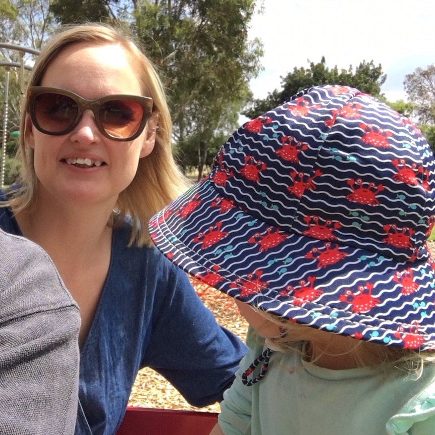 A smiling woman and a young child in a hat