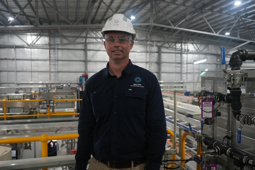 A man in a hard hat stands in a factory