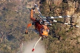 A helicopter water bombs a fire at Badgerys Lookout, near Tallong in New South Wales, January 9, 2012.