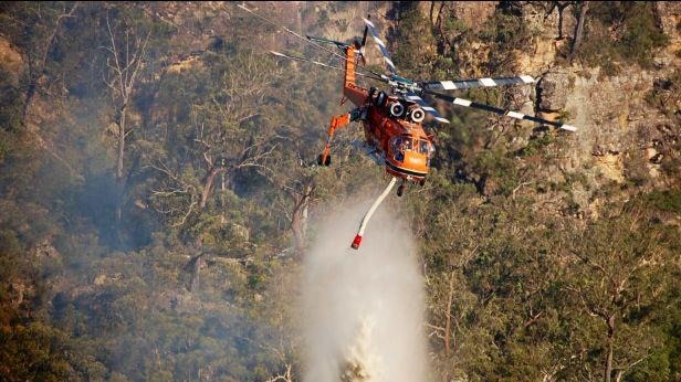 A helicopter water bombs a fire at Badgerys Lookout, near Tallong in New South Wales, January 9, 2012.