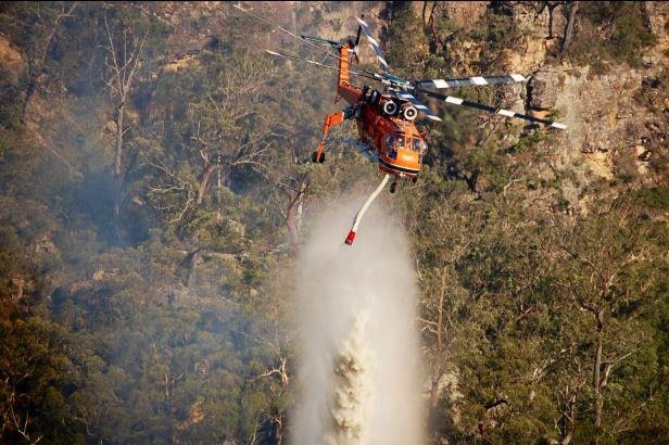 A helicopter water bombs a fire at Badgerys Lookout, near Tallong in New South Wales, January 9, 2012.