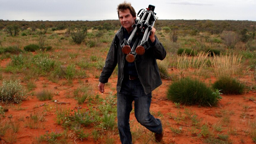 Paul Lockyer carries a camera tripod while on assignment