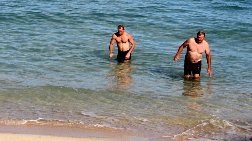 Two men emerging from the ocean.