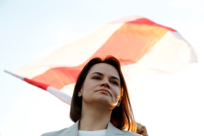 Angled upwards - A woman with shoulder-length brown hair looks over the top of the frame, a red and white flag billows behind