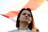 Angled upwards - A woman with shoulder-length brown hair looks over the top of the frame, a red and white flag billows behind