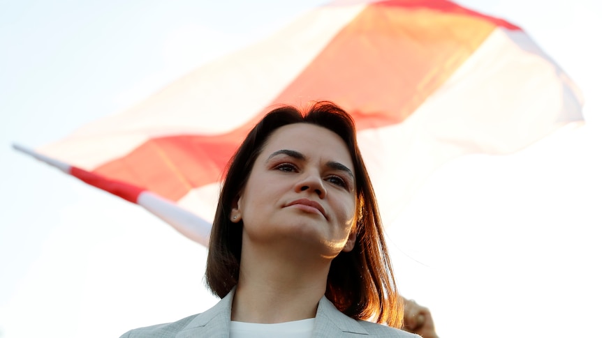 Angled upwards - A woman with shoulder-length brown hair looks over the top of the frame, a red and white flag billows behind