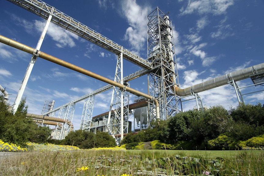 an industrial building with a pond in the foreground.