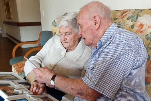 An elderly man and woman looking at photos together
