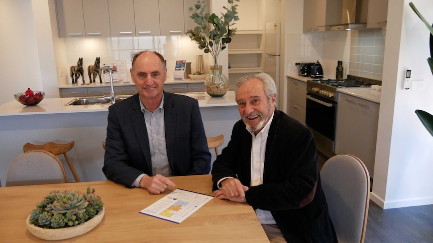 Two men sit at a dining room table.