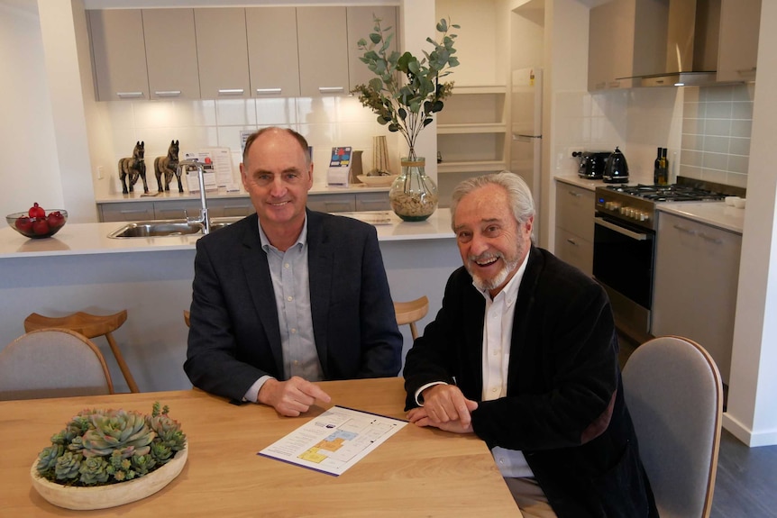 Two men sit at a dining room table.