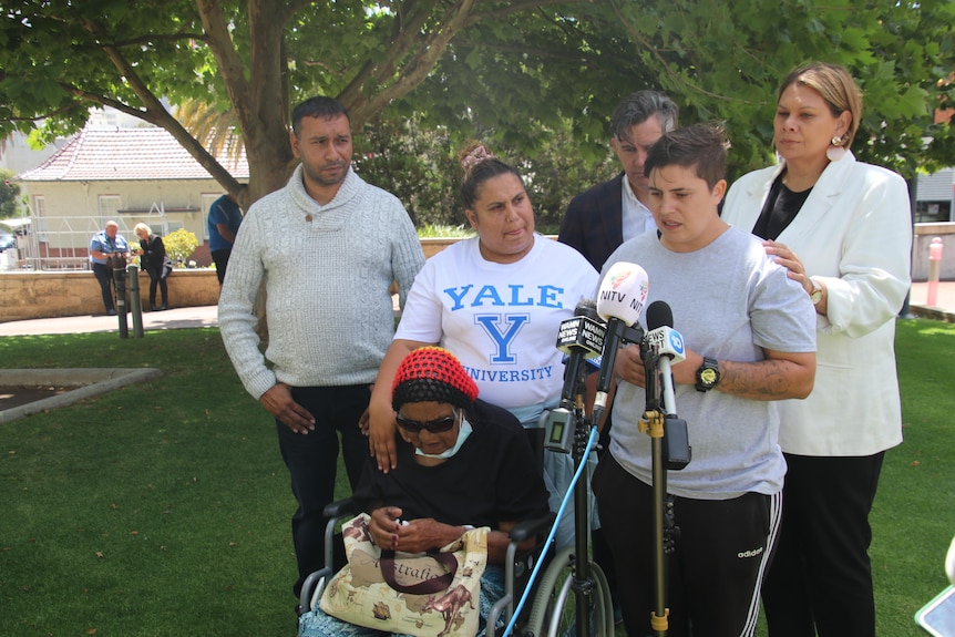 A group pf people address media in a park