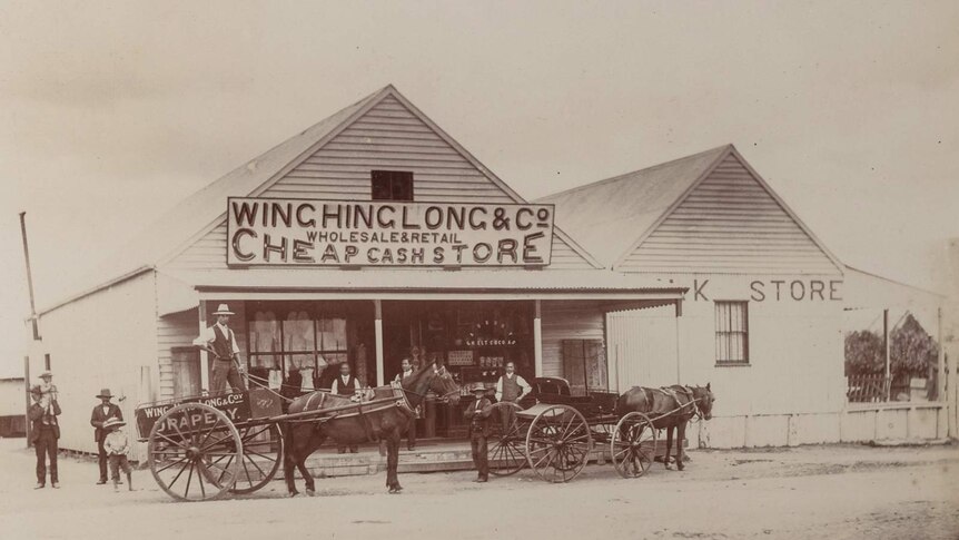 Black and white photograph of the Wing Hing Long store building with men and horses out front.