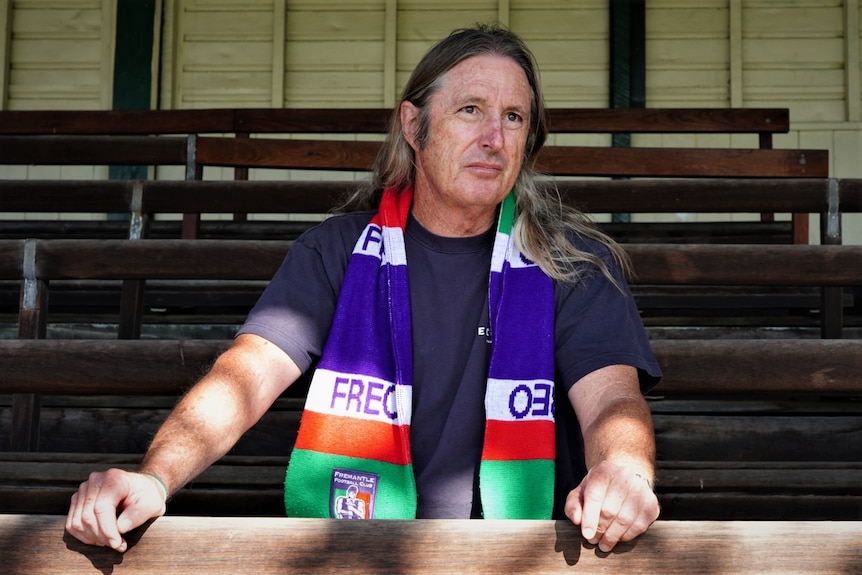 A man wears a Freemantle Dockers scarf