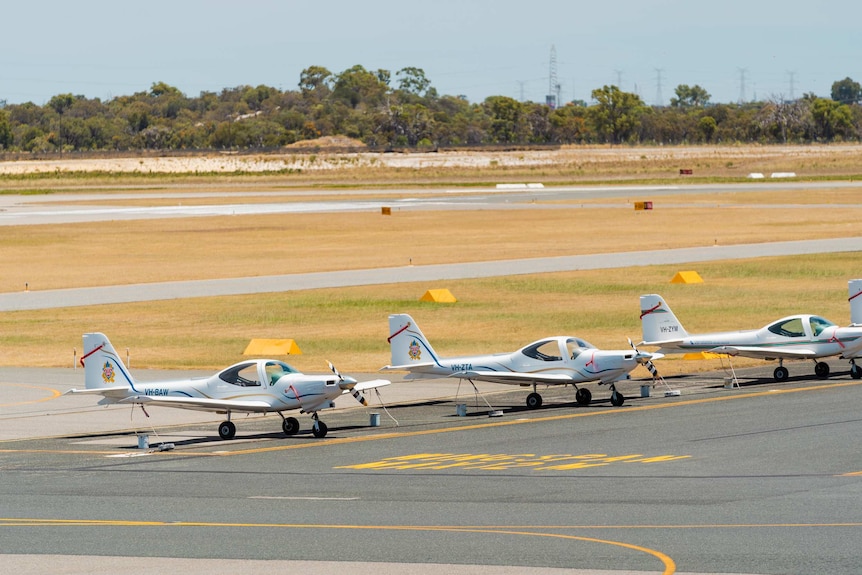A row of small aircraft parked on the tarmac of Jandakot Airport in Perth.