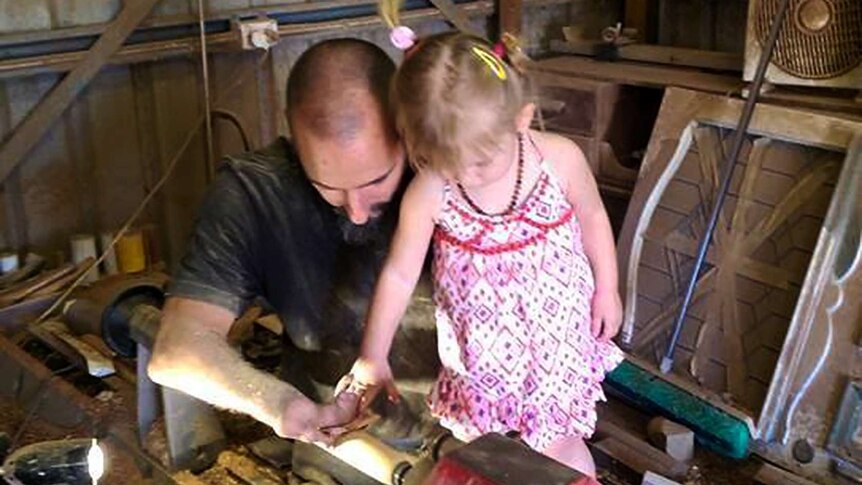 A man teaching his young daughter how to use a wood lathe.