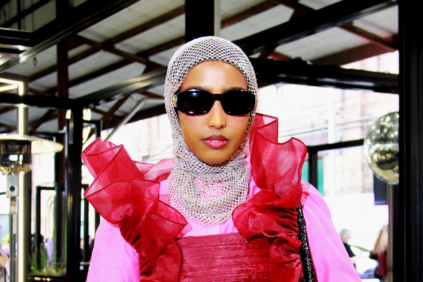 woman in pink dress and sunglasses with crossed hands