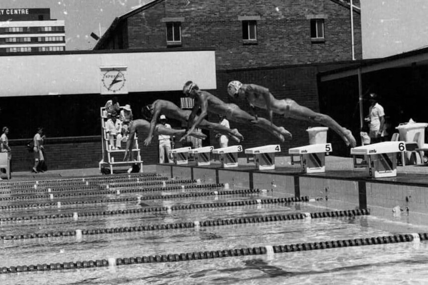 Black and white action shot of swimmers diving