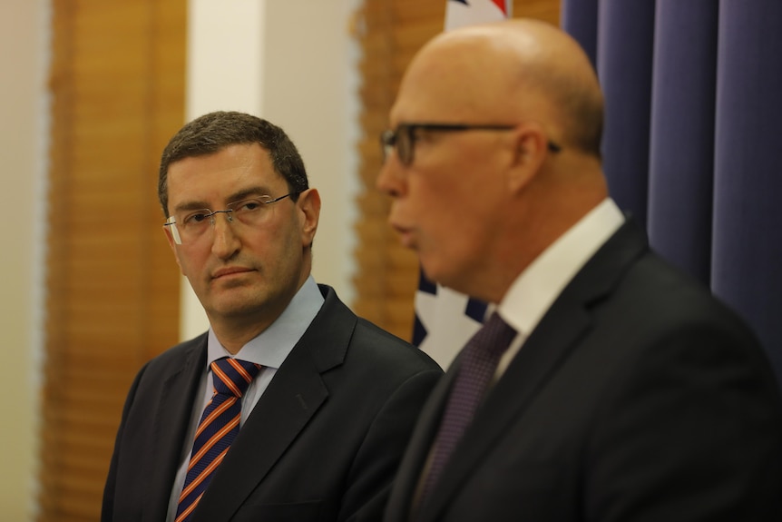 Julian Leeser looks at Peter Dutton at a press conference in the Liberal partyroom
