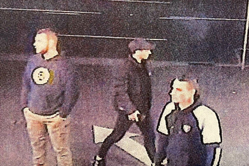 Three men standing around on a footpath