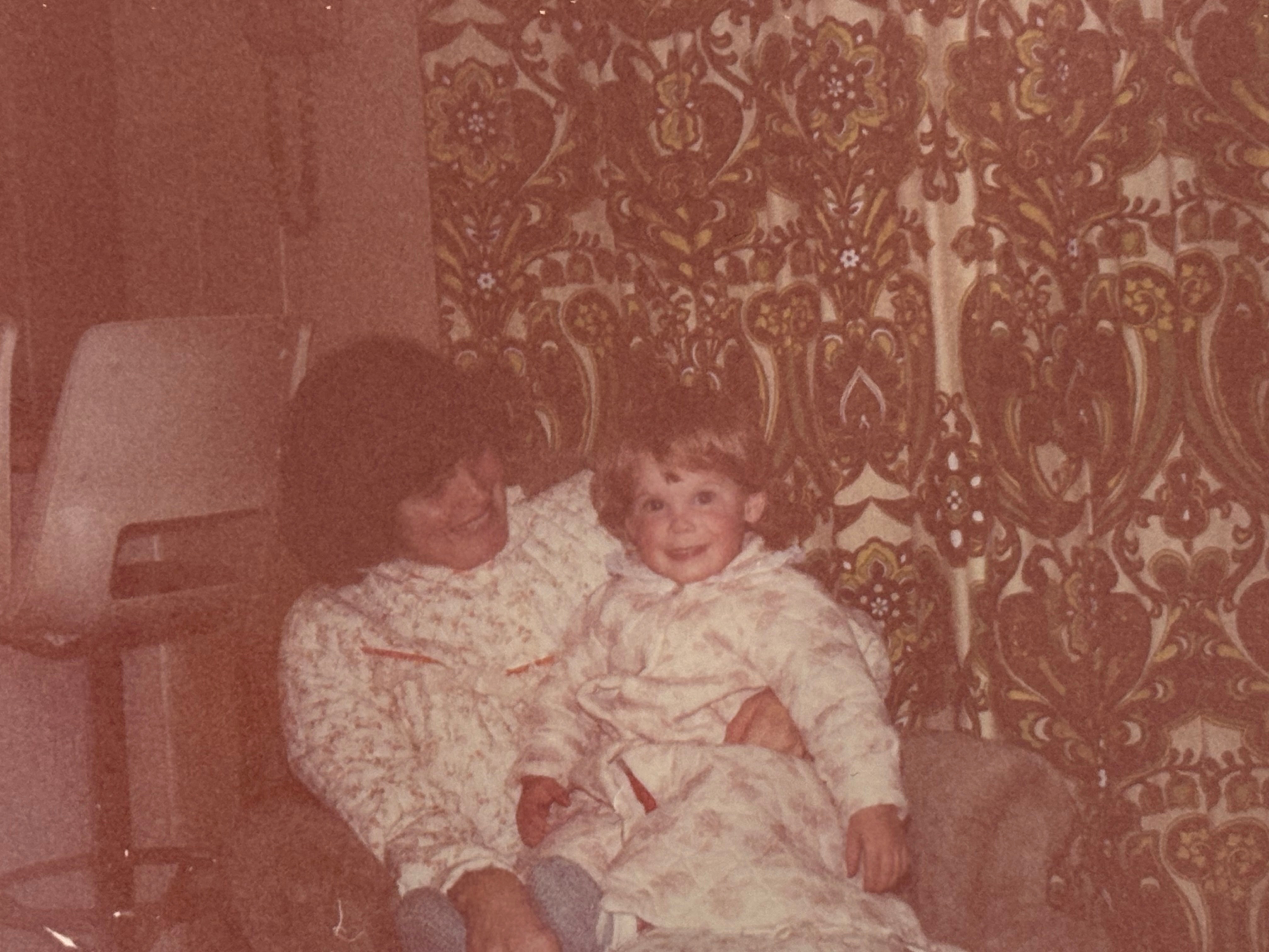 A sepia photo of a woman and child dressed in white smiling
