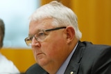 Andrew Metcalfe sitting behind a microphone at a desk in focus, murray watt next to him out of focus