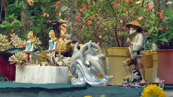 Potted plants in a garden with brightly coloured figurines placed in front of them