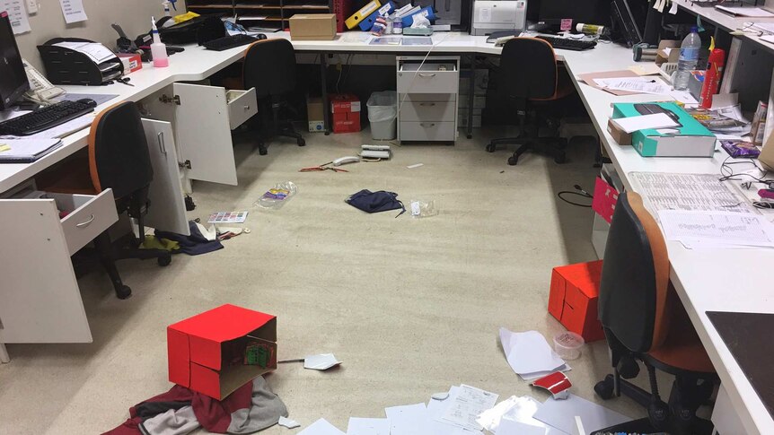 A school office with boxes and items all over the floor and furniture vandalised.