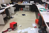 A school office with boxes and items all over the floor and furniture vandalised.
