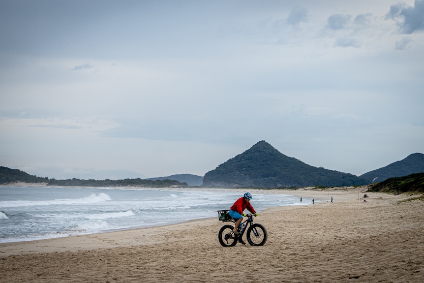 A cyclist riding on the beach at Hawks Nest
