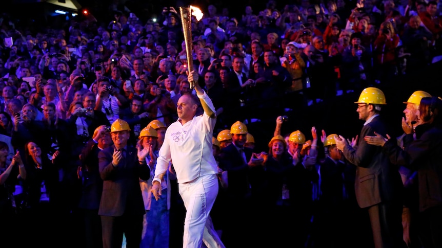 Former Olympic rower and winner of five gold medals, Steve Redgrave, carries the flame into the stadium.