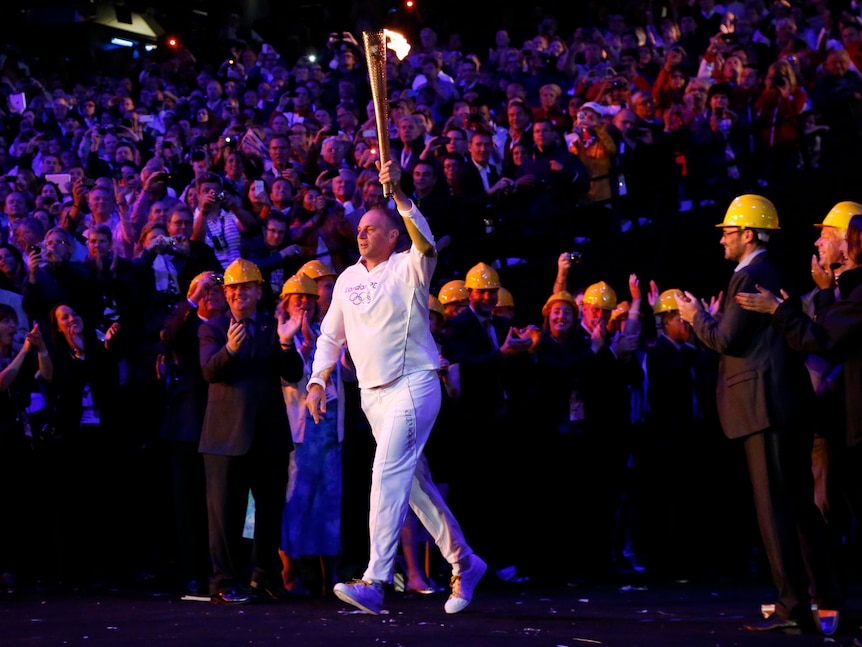 Former Olympic rower and winner of five gold medals, Steve Redgrave, carries the flame into the stadium.