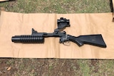 A large black weapon laying on a piece of cardboard on the lawn of a Charlestown home.